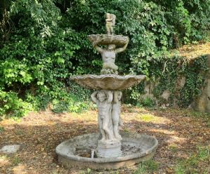 Circular two-tiered stone cascade fountain decorated with cherubs